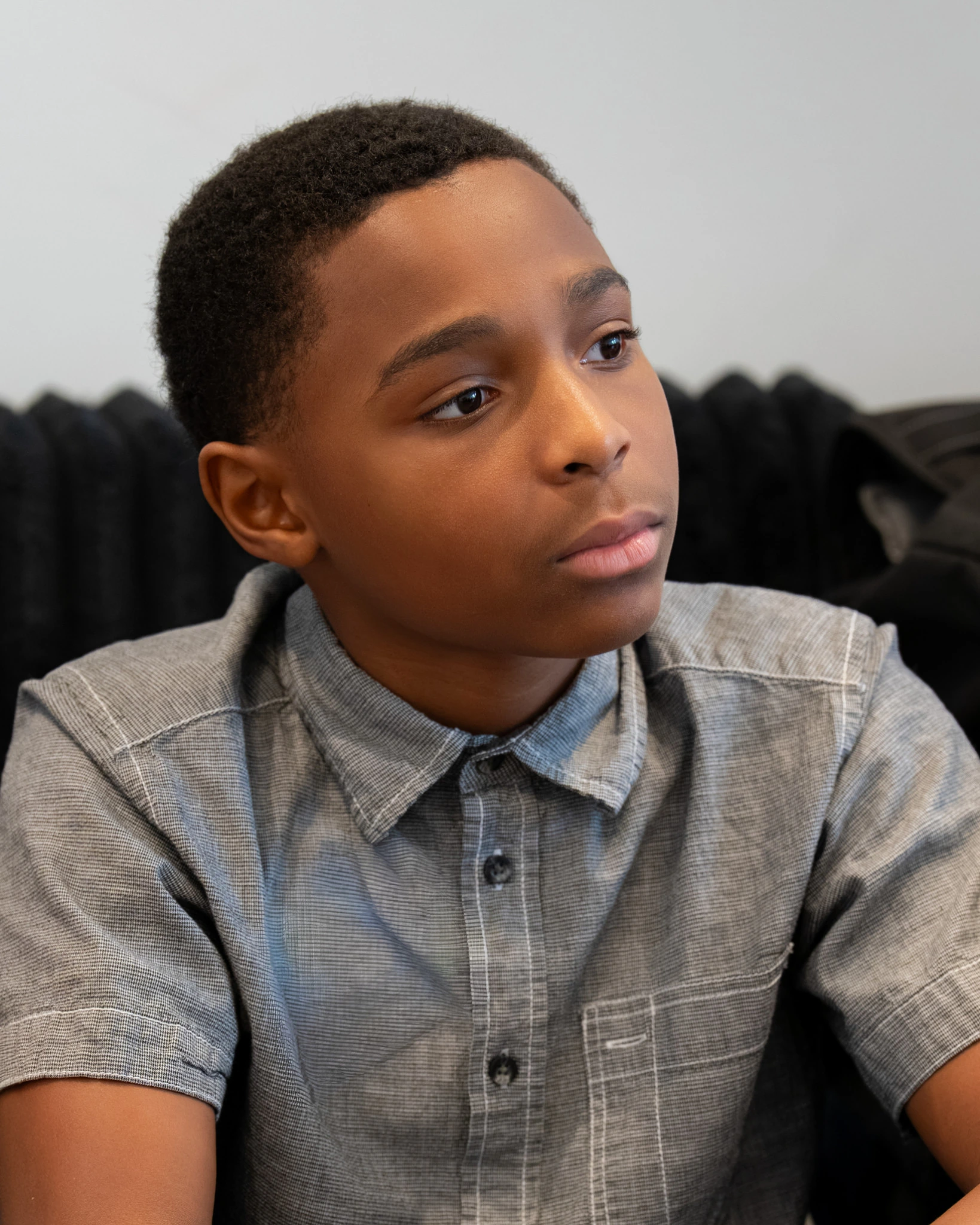 Boy in a gray collared shirt listening during a Bible lesson in the children's room.