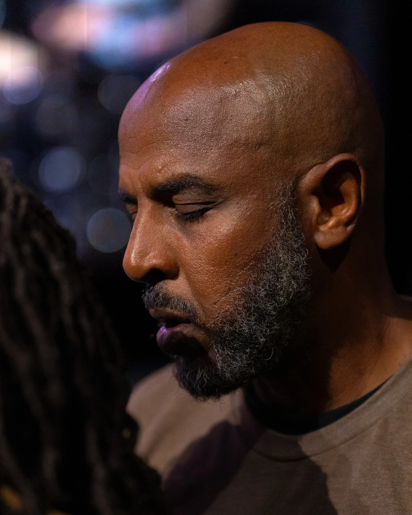 Close portrait of a man with a gray beard and closed eyes during prayer after the service.
