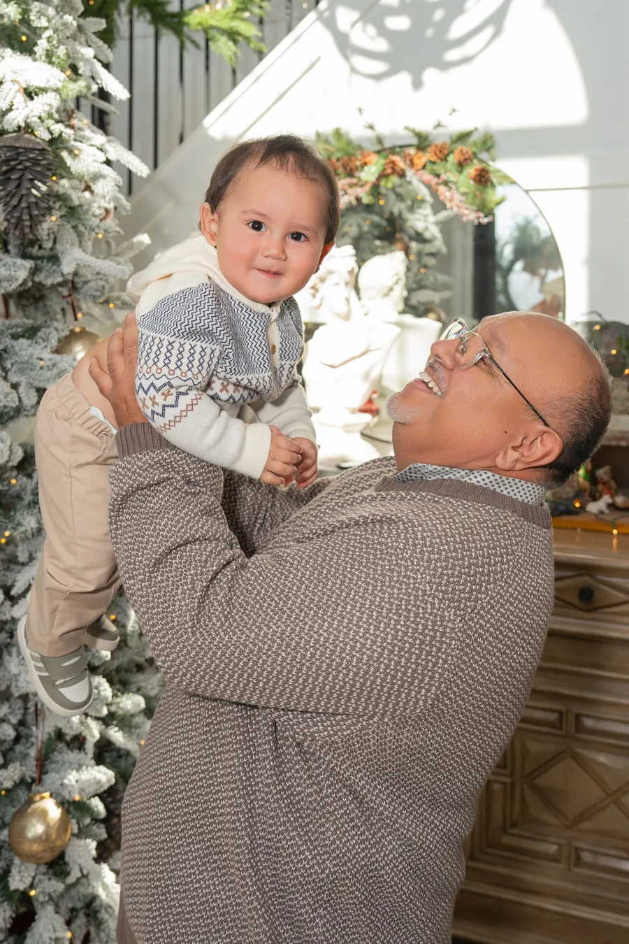 A joyful moment with a baby beside the Christmas tree